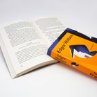 Buchcover mit "Edgar Wallace" und "The Ringer". Ein aufgeschlagenes Buch liegt daneben auf weißem Hintergrund.