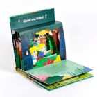 "Hänsel und Gretel" steht oben. Ein Pop-up-Buch zeigt Hänsel und Gretel im Wald vor dem Lebkuchenhaus.