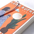 Auf orangem Cover steht „Lena Kupke Roman“. Eine Illustration zeigt eine Person von der Seite mit einer großen Pflanze.