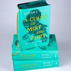Der Titel "A Court of Mist and Fury" von Sarah J. Maas ist in Gelb auf türkisfarbenem Hintergrund. Drei Bücher gestapelt.