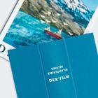 „KRISTÍN EIRÍKSDÓTTIR DER FILM“ steht auf einem blauen Buchcover. Im Hintergrund eine Landschaftsillustration.