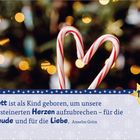 "Gott ist als Kind geboren, um unsere versteinerten Herzen aufzubrechen – für die Freude und für die Liebe." Zwei Zuckerstangen formen ein Herz vor einem verschwommenen Hintergrund mit Lichtern.