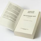Ein geöffnetes Buch mit dem Titel "Das schwarze Haus" von Stephen King und Peter Straub, verlegt vom Wilhelm Heyne Verlag.