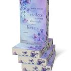 Buchtitel: "Violets woven through our hearts" von Rabia Doğan, Roman. Cover mit violetten Blumen und sanften Pastellfarben.