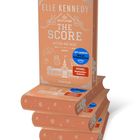 Auf dem Stapel Bücher steht: "Elle Kennedy - The Score. Mitten ins Herz", Text im Hintergrund dekorativ.