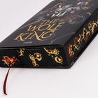 Text: "The Wolf King" und "Cove". Ein Buch mit goldener Verzierung und rotem Leseband.