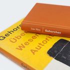 Zwei Bücher mit den Titeln "Gehorchen" von Lisz Hirn, eines mit gelbem Umschlag, liegen gestapelt.
