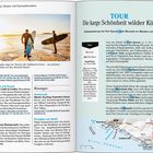 TOUR: Die karge Schönheit wilder Küsten. Zwei Männer tragen Surfbretter am Strand. Infokasten über Küstenspaziergang.