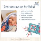 "Sinnesanregungen für Babys" steht oben. Ein lächelndes Baby hält ein Stoffbuch mit Seetieren in der Hand.