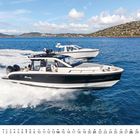 „Windy“ steht auf einem schnellen Motorboot. Zwei Boote fahren nebeneinander auf blauem Wasser, im Hintergrund Berge.