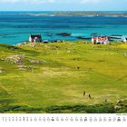 3. 
Ein Fußballfeld auf einer grünen Wiese vor dem Meer. Einzelne Häuser am Horizont, klare, blaue See im Hintergrund.