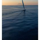 03. Segelboot auf ruhiger See, ferne Vulkaninsel im Hintergrund, Dämmerung, ruhige Wasseroberfläche. Kalenderblatt-Stil.