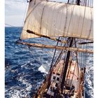 03, Kalender mit Segelschiff auf stürmischer See, voller Segel, holziges Deck, blauer Himmel im Hintergrund.