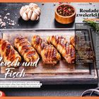 Rouladen mit zweierlei Fleisch, Fleisch und Fisch. Geräucherter Speck umwickelt Rouladen auf Holzbrett, Knoblauch und Pfeffer.