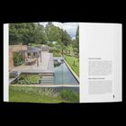 Schwimmen in Hanglage. Links ein moderner Garten mit Schwimmteich, Terrasse, Holzpergola und Seerosen, umgeben von viel Grün.