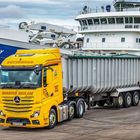 Auf einem Pier steht ein gelber LKW mit „PETERHEAD“, „HARBOUR HAULAGE“, vor einem großen Schiff namens „PATHWAY“.