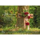 Text: "Aus Liebe ewig leben. Denn also hat Gott die Welt geliebt..." März-Kalenderblatt. Kreuz aus Holz mit Blumen vor Baum.