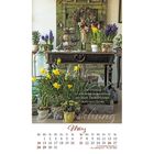 Text: "Der Frühling ist eine echte Auferstehung, ein Stück Unsterblichkeit. – Henry David Thoreau". Kalendarium März. Vor einem grünen Vintage-Schrank ein Tisch mit Frühlingsblumen und dekorativen Elementen.
