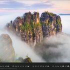 03, Blick auf die Schrammsteine, Elbsandsteingebirge. Große Felsen ragen durch Nebel in die Höhe, umgeben von Bäumen.