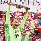 "Der Schriftzug 'März' und ein Kalender. Ein Fußballer in grün jubelt mit einer großen Trophäe, umgeben von Konfetti."