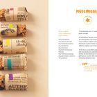 MÜSLIRIEGEL: Rezept mit Zutaten und Zubereitung. Links fünf Müsliriegel in Papier. Tipp zur Lagerung am Bildrand.