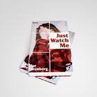 Text "Just Watch Me" und "Lior Torenberg" auf zwei übereinander liegenden Büchern. Cover zeigt abstrakte Kunst.