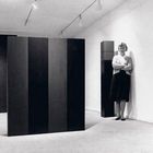 Text: "Anne Truitt at the Andre Emmerich Gallery." Frau steht neben hohen, minimalistischen Skulpturen in einem weißen Raum.