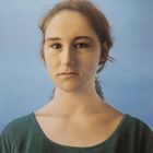 Es gibt keinen sichtbaren Text. Ein realistisch gemaltes Porträt einer jungen Frau mit dunklem Haar vor blauem Hintergrund.