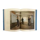 Drei Personen stehen in einem Ziegelraum und schreiben auf Tafeln an den Wänden. Sie sind schwarz gekleidet.