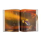 Eine geöffnete Buchseite zeigt eine Illustration von Fischen in einer orangenen Unterwasserlandschaft.