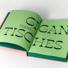 Text: "GIGAN-TISCHES TOKIO". Offenes Buch mit grünem Papier und schwarzen Großbuchstaben.