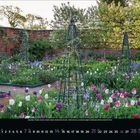 März Kalender, Blumengarten mit Tulpen und Rankhilfen, umgeben von Ziegelmauer und Bäumen.