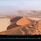 März 2023 Kalender. Wüstenlandschaft mit geschwungenen Sanddünen unter Nebel. Sand in leuchtendem Orange und Beige.