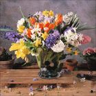 Ein Glasvase mit bunten Frühlingsblumen, darunter Tulpen und Narzissen, steht auf einem Holztisch, umgeben von Blumentöpfen.