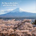 Zitat: „Der Weg zu allem Großen geht durch die Stille.“ - Friedrich Nietzsche. Im Hintergrund: Ein Berg mit Kirschblüten.