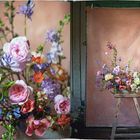 Links ein üppiges Bouquet mit Rosen und Wildblumen; rechts ein Arrangement vor rosa Stoffhintergrund auf Holzstuhl.