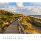Kalender für März; Foto von Dünen auf Sylt, Schleswig-Holstein. Holzweg führt durch grasige Landschaft am Meer entlang.