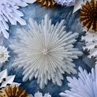 Keine Texte zu erkennen. Geometrische Papierfächer in Weiß und Braun auf einer strukturierten, blauen Oberfläche.