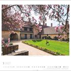 Schloss Cecilienhof, Neuer Garten, Potsdam. März 2027 Kalender mit Magnolienblüten vor einem historischen Gebäude und Rasen.
