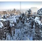 Bastei: Die berühmte Basteibrücke in schneebedeckter Landschaft der Sächsischen Schweiz, umgeben von majestätischen Felsen.