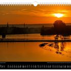 März-Kalenderblatt mit Sonnenaufgang über einer Stadt und einem Fluss im Vordergrund.