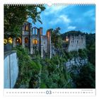 03. Steinburg auf Klippe, umgeben von Wald, beleuchtet in der Dämmerung. Eindrucksvolle Architektur mit Bögen und Türmen.