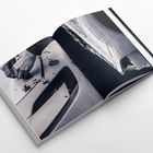 Kein erkennbarer Text. Ein geöffnetes Buch zeigt Fotos: Hände schnitzen Holz, Späne liegen darauf.