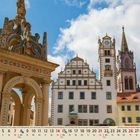 03. Mönchengladbach. Aufnahme von historischen Gebäuden mit Turm und verziertem Brunnen unter blauem Himmel.