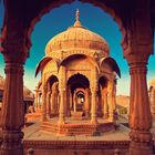 Eine prächtige, kunstvoll geschnitzte Sandsteinarchitektur mit gewölbten Dächern und Säulen vor klarem Himmel.