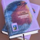 „Clare Chambers, Heimliche Zeilen, Roman.“ Zwei Bücher mit einem Rotkehlchen auf violettem Cover.