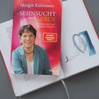Covertext: "Sehnsucht nach Leben", Margot Käßmann. Darunter Porträt einer Frau. Im Hintergrund ein offenes Buch mit Illustration.