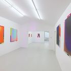 Leuchtende, abstrakte Gemälde in kräftigen Regenbogenfarben hängen an hellen, weißen Wänden einer modernen Galerie.