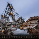 Kalender mit Zahlen von 1 bis 31 und Wochentagen darunter. Großes Industriemaschinenrad im Einsatz.