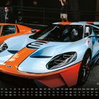 Ford GT 40, Nummer 3 am Bildrand. Zwei Sportwagen in Blau-Orange und Orange. Hintergrund: Zuschauer mit Kamera.